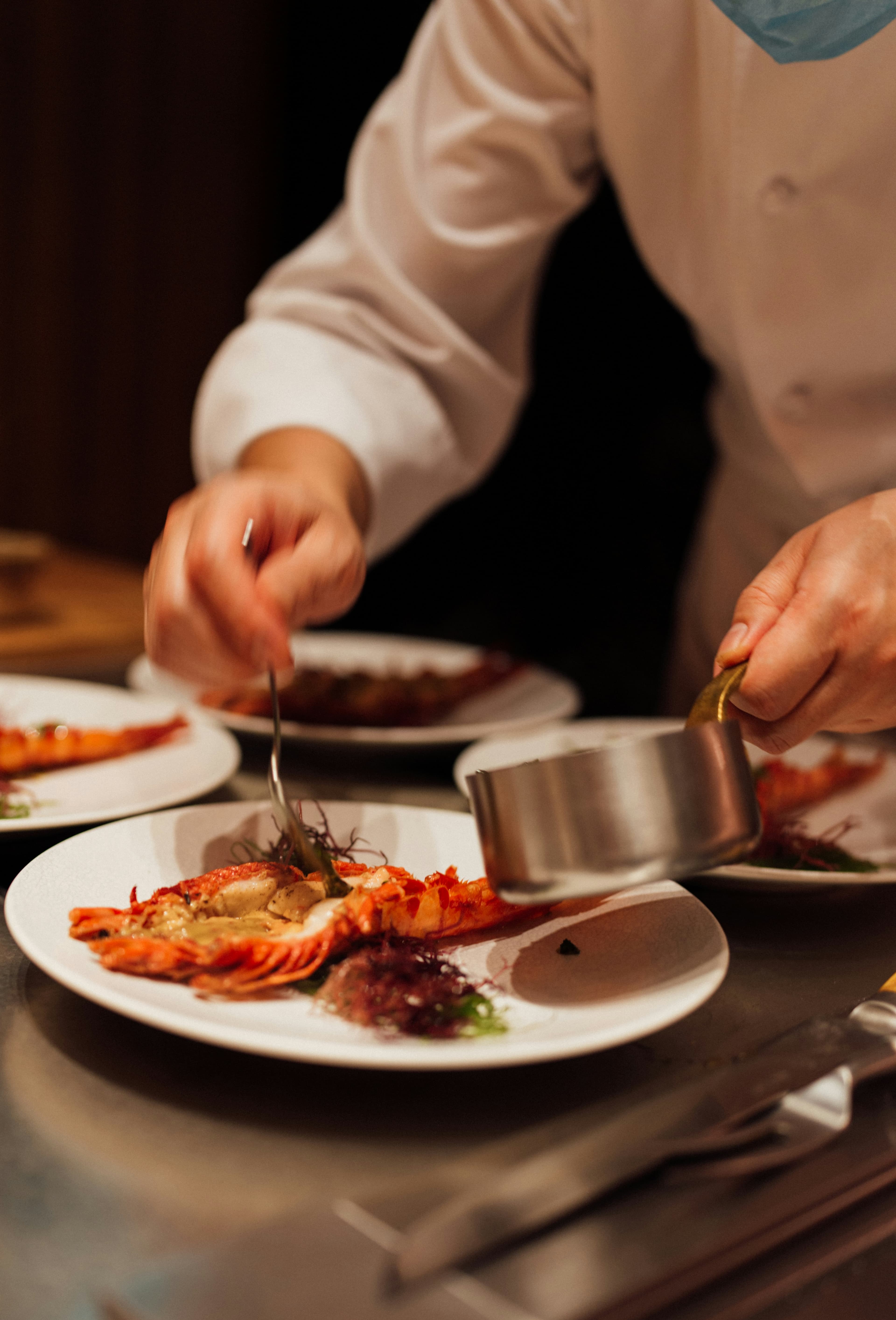 Personal chef plating lobster with delicate precision